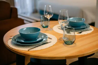 a wooden table with plates and wine glasses on it at Villa Teresa apartamentos in Vila Nova de Gaia