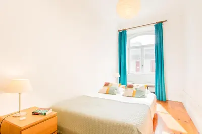 a bedroom with a bed with blue curtains and a window at Charming Historic 31 Janeiro Street in Porto