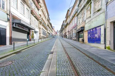 an empty street with train tracks in a city at Charming Historic 31 Janeiro Street in Porto