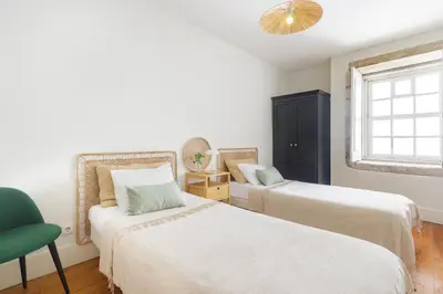 a bedroom with two beds and a green chair at Charming Historic 31 Janeiro Street in Porto