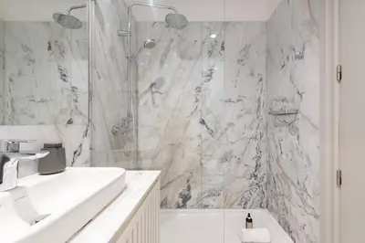a white bathroom with a shower and a sink at LovelyStay - Deluxe 2BR Duplex with Splendid View in Porto
