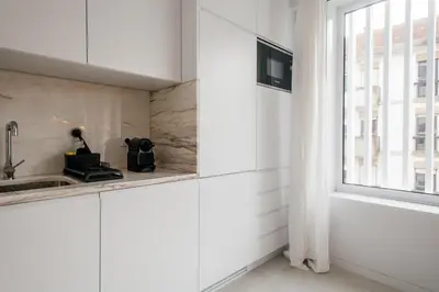 a white kitchen with a sink and a window at Nomad's Easy Stay - 1BED Porto Marquês in Porto