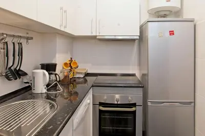 a kitchen with white cabinets and a stainless steel refrigerator at O´Porto Torrinha Flat in Porto