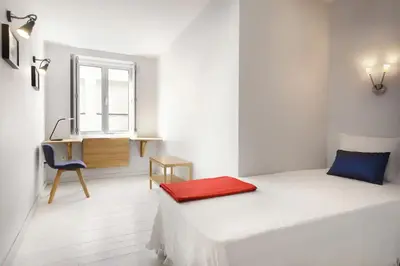 a bedroom with a bed and a desk and a window at O´Porto Outeiro Flat in Porto