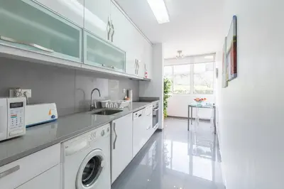 a white kitchen with a washing machine and a sink at O´Porto Fontinha Flat in Porto