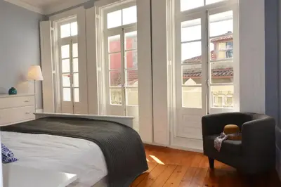 a bedroom with a bed and a chair and windows at Bonjardim 466 - Historic Townhouse in Porto