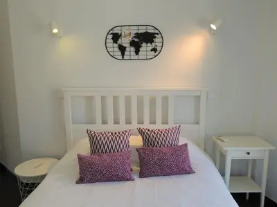 a bed with two purple pillows and a clock on the wall at Rendez Vous Porto II in Porto