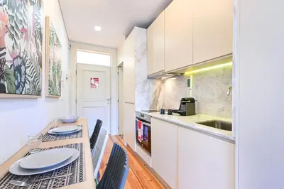 a kitchen with white cabinets and a table and chairs at ON Apartments - Garden View 2 in Porto