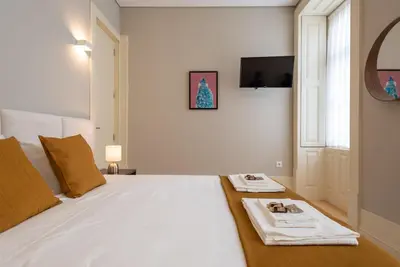 a bedroom with a white bed with a tv on the wall at CC Downtown Palace - G in Porto