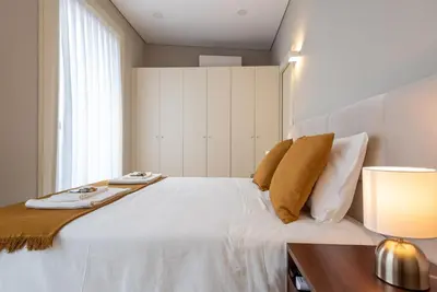 a bedroom with a white bed with a table and a lamp at CC Downtown Palace - I in Porto