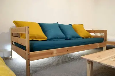 a wooden couch with blue and yellow pillows on it at Rian - central 2 bedroom Apartment in Porto in Porto