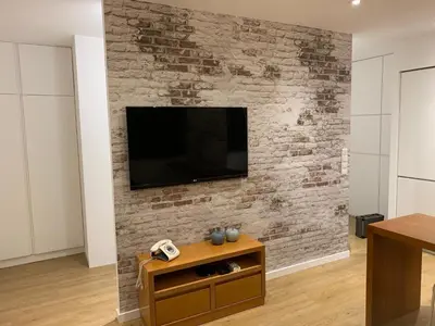 a living room with a tv on a brick wall at Palace House Apartment in Porto