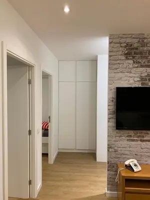 a living room with a television and a brick wall at Palace House Apartment in Porto