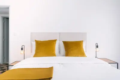 a bedroom with a white bed with yellow pillows at D&S - Family Apartments I in Porto