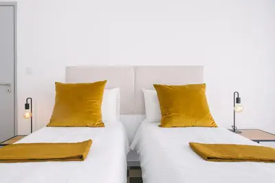 two beds with yellow pillows in a bedroom at D&S - Family Apartments I in Porto