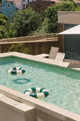 a swimming pool with two lawn chairs and two swimming tubes at JAM Porto in Porto
