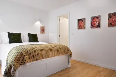 a white bedroom with a bed and some pictures on the wall at Oporto Classic Terrace in Porto