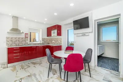 a kitchen with red cabinets and a table and chairs at Maredimo Village Casa 3 in Porto
