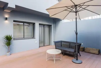 a patio with a bench and an umbrella at GuestReady - Three Mirrors in Porto