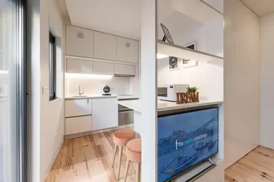 a kitchen with white cabinets and a flat screen tv at GuestReady - Three Mirrors in Porto