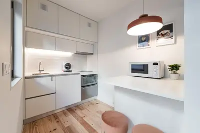 a white kitchen with a sink and a microwave at GuestReady - Three Mirrors in Porto
