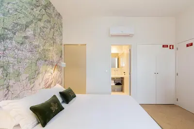 a bedroom with a white bed with a map on the wall at Casa de Arouca Porto Apartments in Porto
