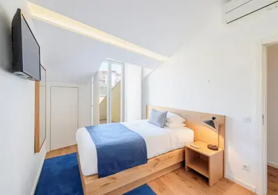 a bedroom with a bed and a flat screen tv at Mouzinho da Silveira Unique Apartments, by Oporto Collection in Porto