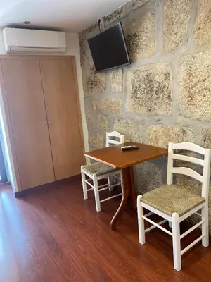 a table with two chairs and a tv on a stone wall at PORTO RICO STUDIOS in Porto