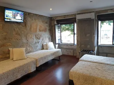 a room with two beds and a tv on the wall at PORTO RICO STUDIOS in Porto