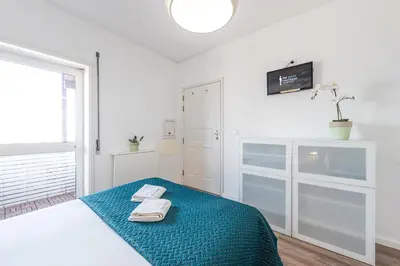 a white room with a bed with two towels on it at GuestReady - Red Stripes in Porto
