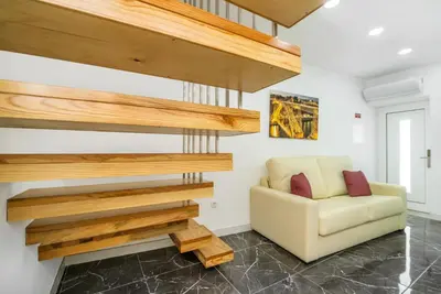 a living room with a yellow chair and wooden stairs at Maredimo Village Casa 6 in Porto