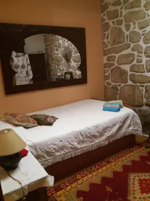 a bed in a room with a stone wall at Al Pinheiro 66 in Porto