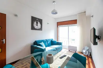 a living room with a blue couch and a tv at Oporto Trindade Downtown in Porto