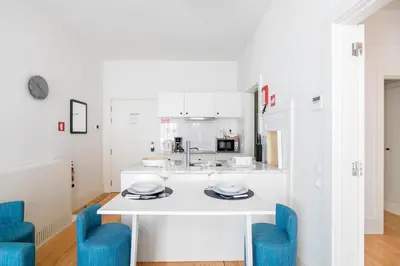 a white kitchen with blue chairs and a counter at Oporto Flores Plaza by LovelyStay in Porto