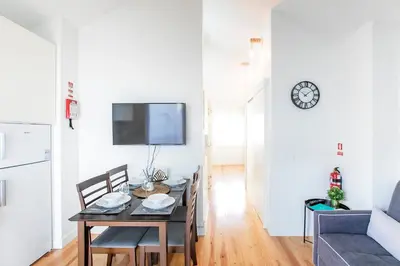 a dining room with a table and chairs and a tv at LovelyStay - Cozy 1BR in Santa Catarina w/ Balcony in Porto