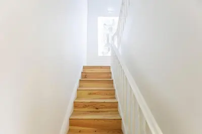 a staircase in a white room with wooden floors at LovelyStay - Cozy 1BR in Santa Catarina w/ Balcony in Porto