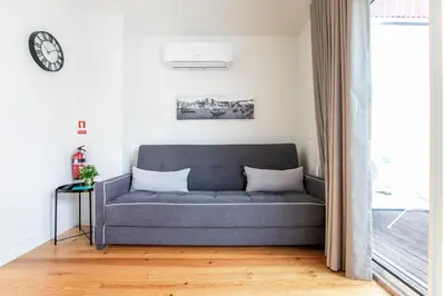 a couch in a living room with a clock on the wall at LovelyStay - Cozy 1BR in Santa Catarina w/ Balcony in Porto