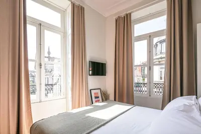 a bedroom with a bed and two large windows at Oportments - S.Bento in Porto