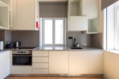 a white kitchen with white cabinets and a window at Prime Riverside in Porto