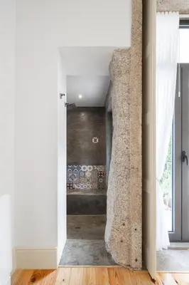 a bathroom with white walls and a stone wall at Uba - Heritage and Wine in Porto