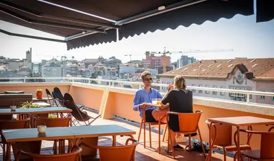 two people sitting at tables on a balcony at Ceuta Terrace Suites in Porto