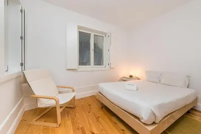 a bedroom with a bed and a chair and a window at GuestReady - Triple C's in Porto