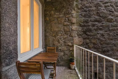 a wooden bench next to a stone wall with a window at GuestReady - Triple C's in Porto