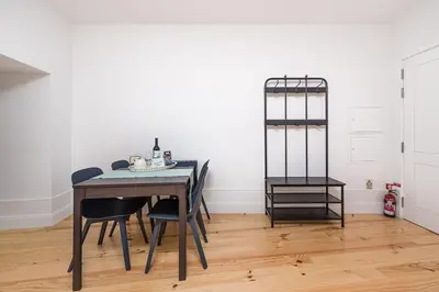 a table and chairs in a room with a white wall at GuestReady - Triple C's in Porto