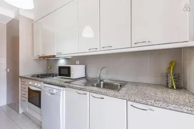 a white kitchen with a sink and a microwave at Gaia House - Apartamento com Metro à Porta e Centro Histórico Perto in Vila Nova de Gaia