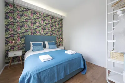 a bedroom with a blue bed with a floral wallpaper at Sta Catarina - 2 Bedroom Apartament in Porto