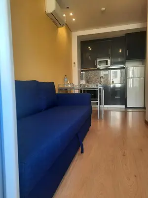 a blue couch in a living room with a kitchen at Apartamentos Portodouro - Santa Catarina in Porto