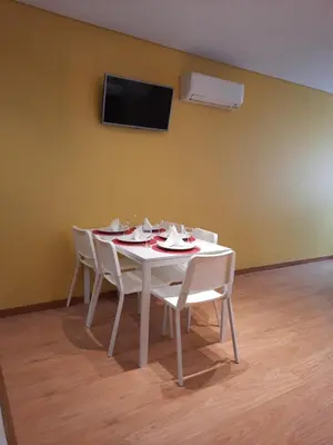 a white table with white chairs and a tv on a wall at Apartamentos Portodouro - Santa Catarina in Porto