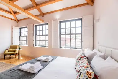 a bedroom with a large bed in a room with windows at Newly Renovated Cozy Central Loft w/ AC by LovelyStay in Porto