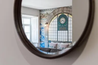 a mirror reflecting a room with a clock on the wall at GuestReady - Nature-themed Studio in Porto